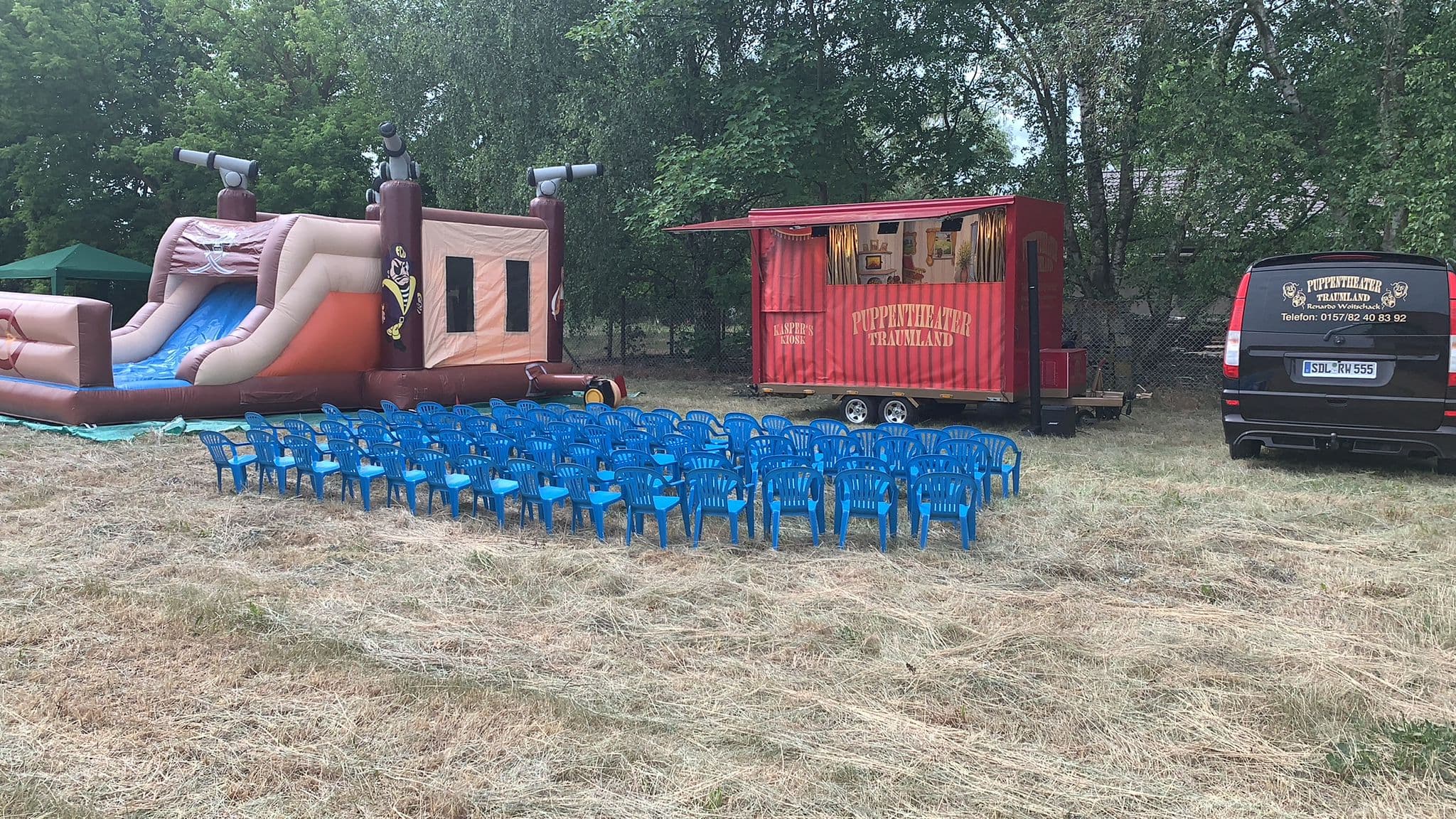 Aufgebauter Spielplatz mit Hüpfburg und blauen Kinderstühlen