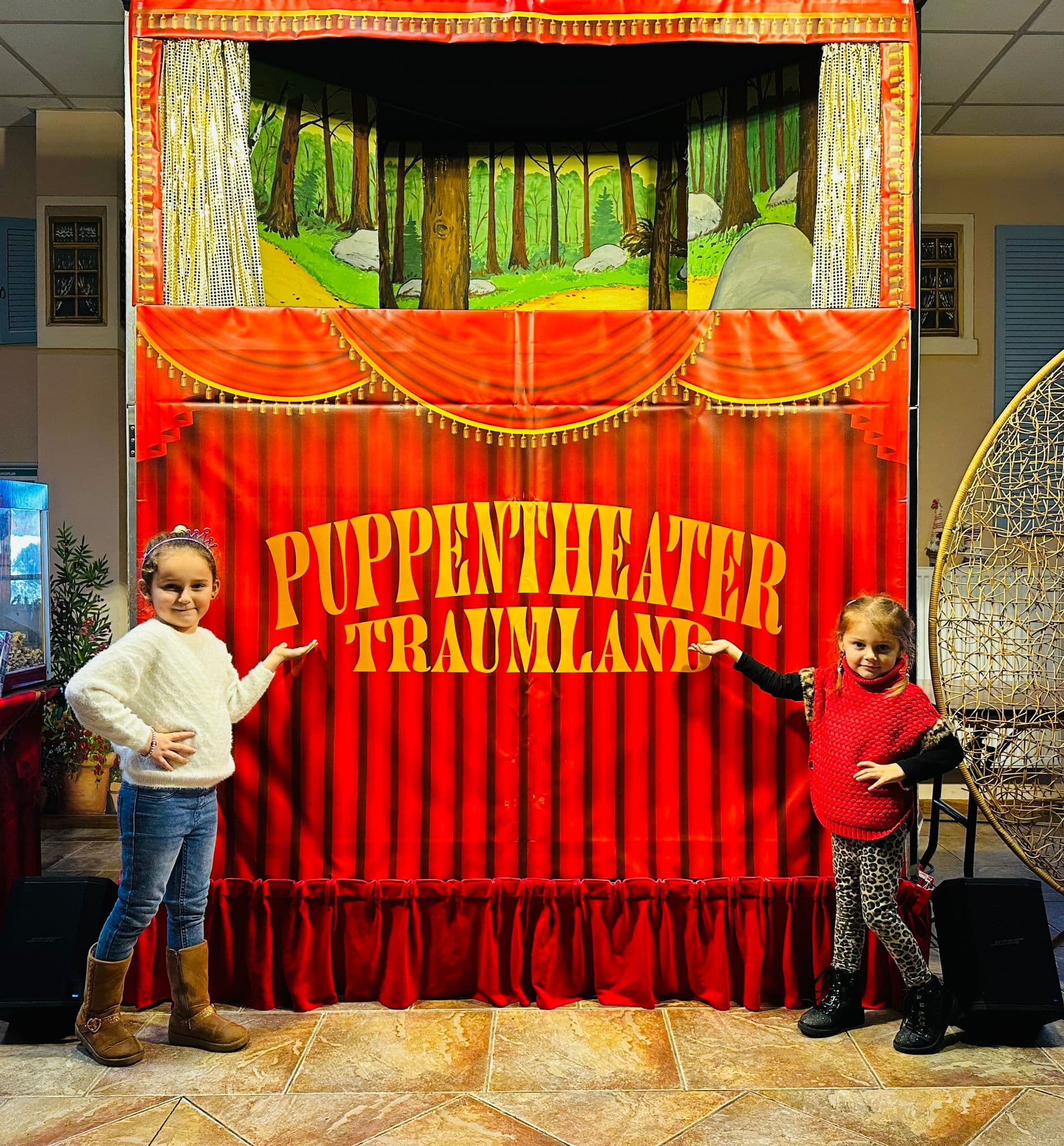 Zwei Mädchen präsentieren stolz die rote Bühne von Puppentheater Traumland