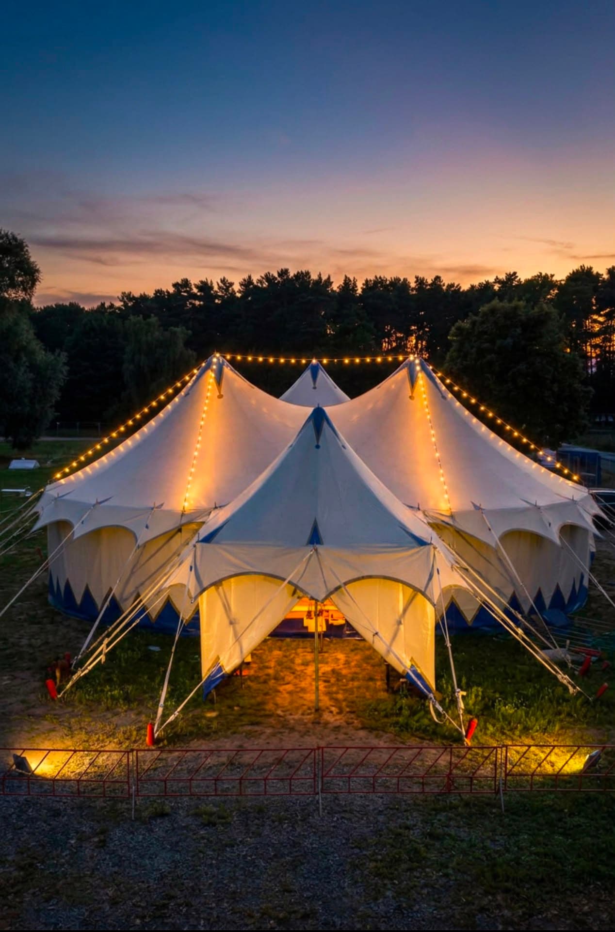 Das Theaterzelt bei Sonnenuntergang mit leuchtenden Lichterketten