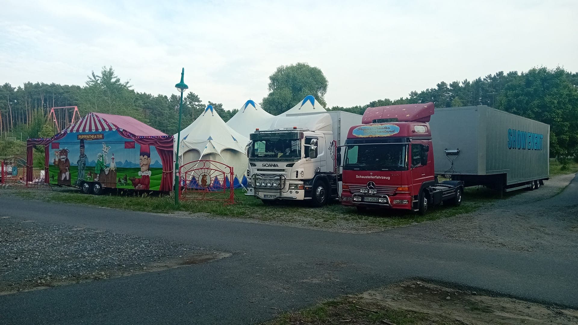 Theaterzelt mit blau-weißen Spitzen neben dem LKW